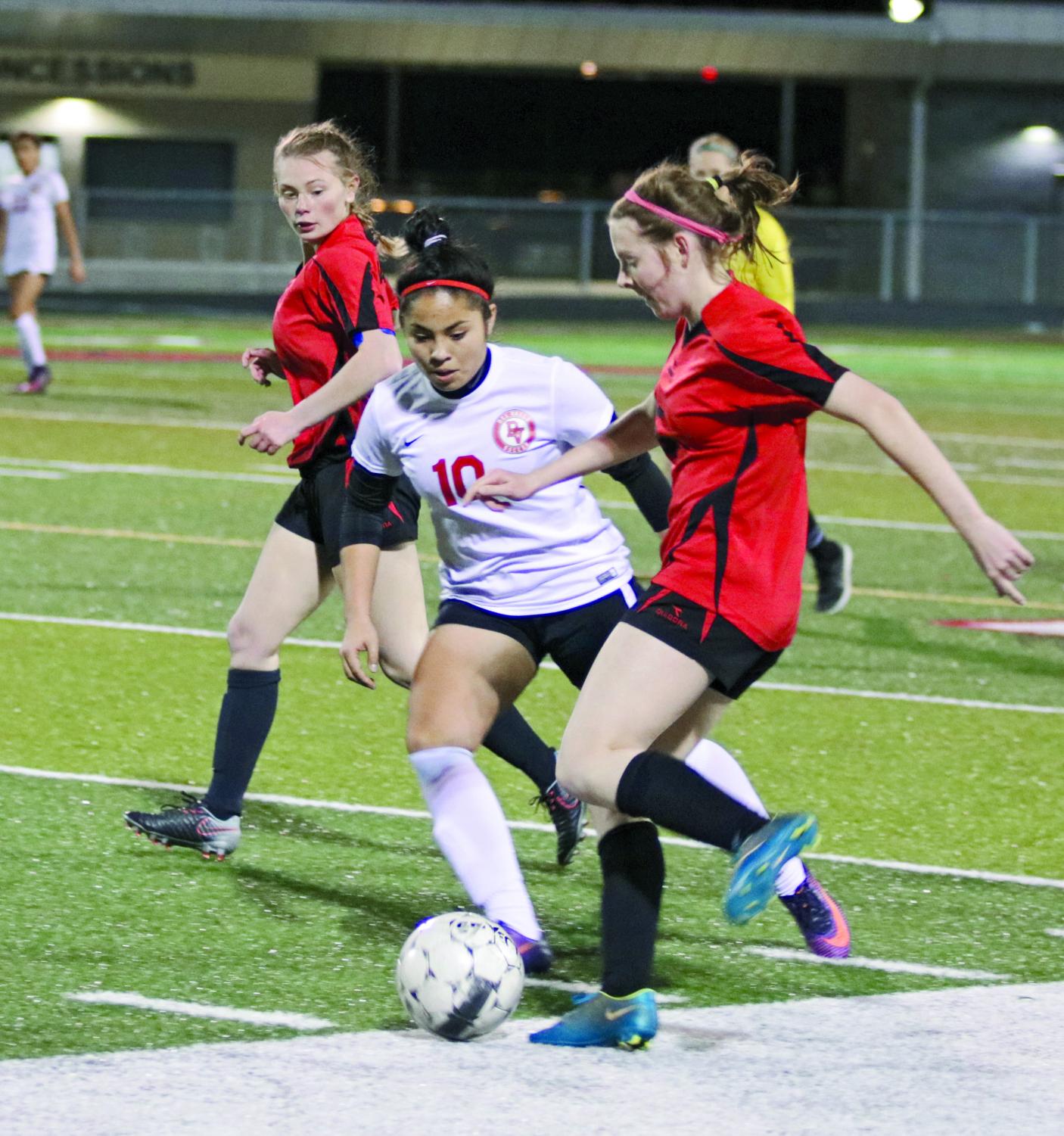PLANT AND PASS: Junior Bergan Bible prepares to make a pass past Del Valle junior Xenia Abarca as junior Hannah Hall watches. On February 19 the girls are scheduled to face off against Del Valle again in a home game.