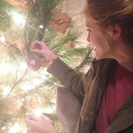 Junior Lily Howard puts her homemade ornaments onto the Christmas tree. She makes this decoration annually by using pins, fabric, and Styrofoam to create a fun, decorative look. “They look really impressive and difficult to make but its actually really fun and almost anyone could to it,” Howard said.