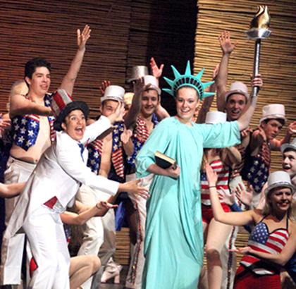 Belana Torres, portraying the Engineer in Miss Saigon, welcome Dana Havlin, playing the Statue of Liberty, on stage during The American Dream. Nearly the entire acting cast is on stage in full costume and makeup performing the second to last number in the musical. The orchestra practiced after school for nearly every rehearsal along with the actors, directors, and technicians.