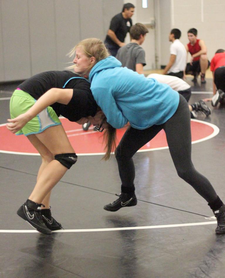 Junior Kimberly Gill  has her teammate  in a head lock during an after school practice. The wrestling team practices after school every day to perfect their skills.