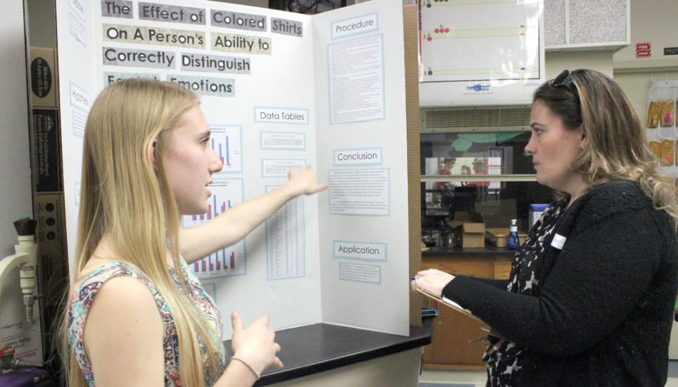 Sophomore Madison Felux shows off her science fair project to a judge. Students have worked hard on the their projects, some starting in the summer.