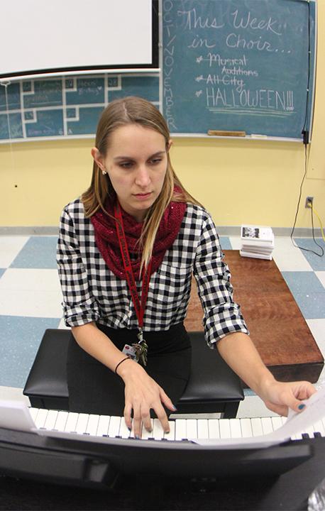 Wearing a warm scarf and pencil skirt, choir and guitar teacher Caitlin Gasco plays along with her guitar class. She dressed in a fall flannel and pencil skirt, trends of the season.