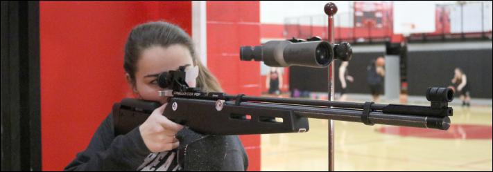 Junior Hope Ritchie aims for her target during shooting practice. Colonel Robert Downey, the instructor for Junior ROTC Marksmanship, holds target practice in the gym after school, when those on the marksman team practice shooting with wooden targets on a wall.