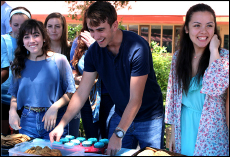 Seniors Nick Anaghos, Julianna Davis, and Kerry McGillicuddy smile while passing out sweets to students wearing blue. PAL students pass out food every year during the celebration. 