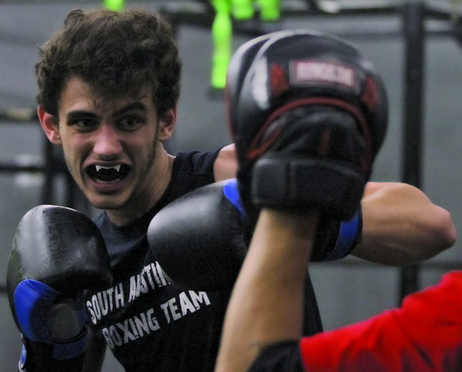 FIGHTING WITH FANGS: While in the middle of sparring practice with his coach, junior Evan Janowitz shows off his fang-painted mouth guard before throwing a punch.  The sport requires many mental aspects that Janowitz wants to improve on such as being able to have a stronger central focus,  PHOTO BY Austyn Keetly