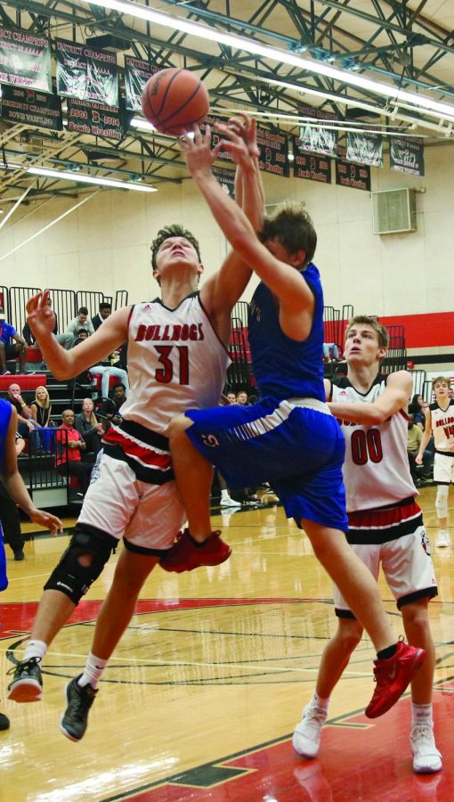 REACHING FOR THE REBOUND: Senior Braden Gough goes up for a rebound against defensive player in a tournament game against Saint Andrews as junior Carson Donahue watches. Braden has played basketball at Bowie all four years and this is his second year on the varsity team. 