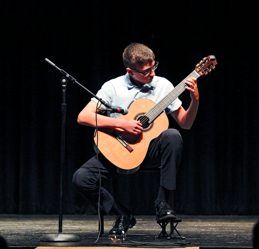 STRUMMING SOLOIST: Freshman Leif Tilton plays a 14 minute solo of the Turkish song, Koyunbaba. He began playing guitar when he was six and has loved it ever since.