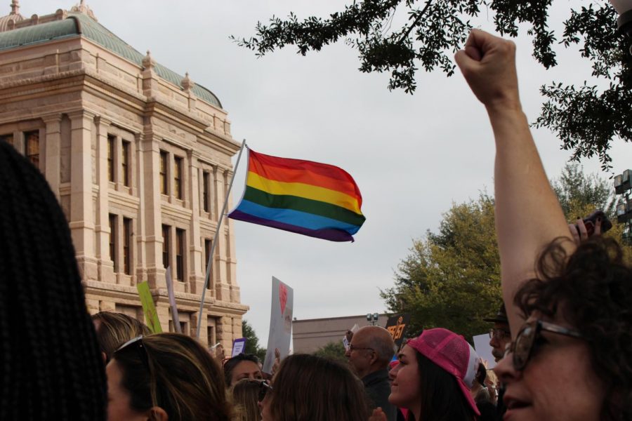 The LQBTQ Pride flag is shown being held up in the 2018 Womens March with a supporter of womens rights holding up her fist to show support of the rally. Wendy Davis is speaking to the the gathering of record breaking amount supporters.