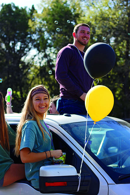 PREACHING KINDNESS: Throwing out candy to students, senior Camille Seminet and junior Peyton Ludemann ride in the student leadership  oat. Student leadership started preparing for the parade at the beginning of the spring semester. “Well we’d been preparing for the parade for
a while and just tried to get as many people involved as possible, and I think that’s a big part of what made it so big and fun this year,” Seminet said. 