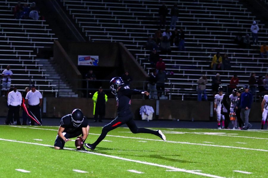 HERE’S THE KICKER: Sophomore Josh McCormick kicks a field goal as senior Aiden Ellisor holds the ball in place. McCormick, Ellisor, and the Bowie Bulldogs won the game against  the Akins Eagles 49-29 with McCormick drilling seven extra points to stay perfect this season. 