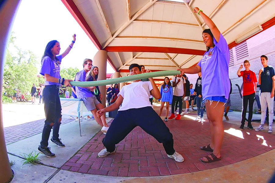 CHEERING ON: Seniors Alexa Robinson and Taylor Bhuiyan cheer on Junior Hector Garcia as he bends back while playing limbo. The Bowie carnival consisted of many different games and activities which the students could participate in. “I thought the carnival was really fun time and a good way to relieve some stress,” Bhuiyan said. “It  brought Bowie students together despite our differences.”