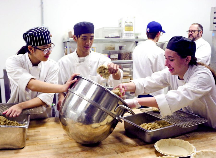 DIGGING IN: Seniors Asia Vo, Joseph Mao, and Grace Mansen dig in to make the oatmeal crumble for their apple pies. They spent the bulk of the day running the dough over the grates to make enough for all their pies. “The apple pie was my favorite, the crumble was especially fun to make,” Mao said. 