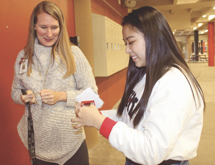 LENDING SOME LOVE: Senior Lin Tran helps Cindi Carroll hang badges on teachers doors after school. Tran helps out Carroll of ten as part of Helping Hands. 