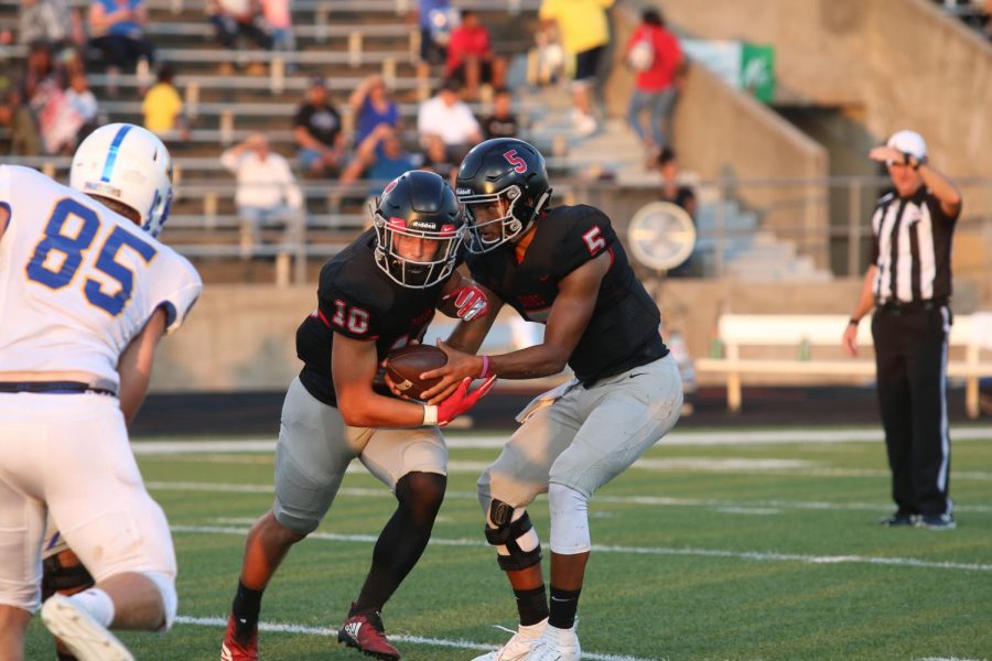 HAND OFF: Quarterback Trinidad Sanders, senior, hands the ball off to senior running back Justin Poole.