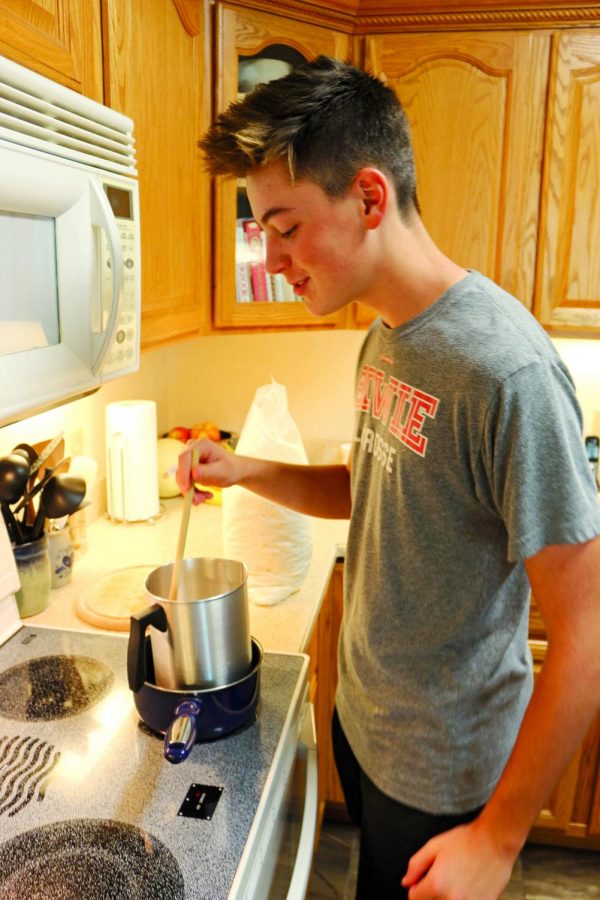 MIXING IT UP: Mid-stir, junior Caden Cooper melts wax to make his homemade candles.  Cooper’s candle company has been making substantial profits lately and is projected to make even more in the coming months.