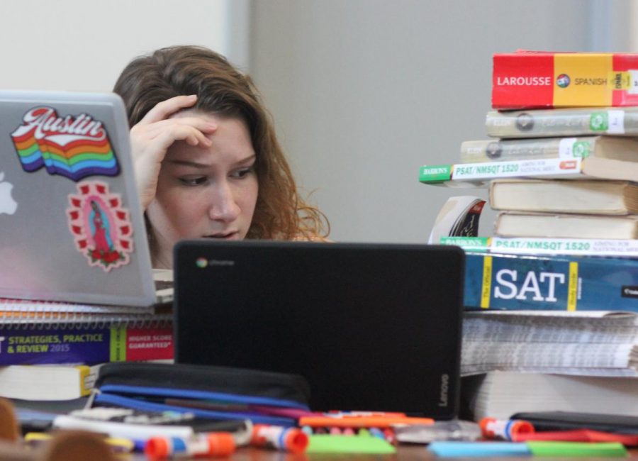 A SEA OF PAPER: Senior Elizabeth Cluchey poses as a student overwhelmed by hoards of test preparation, work, and study material. Substantial workloads are a driving cause behind student movements for homework restrictions and policy reforms. 