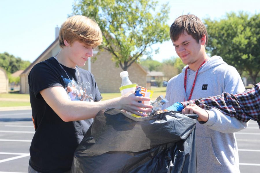 CLEANING UP FOR GOOD: Tye Frnka and Evan Mallett discard litter from the West Oak Woods Baptist Church parking lot with fellow club members. Various clubs have been cleaning up the parking lot for the past month in order to maintain parking lot privileges. 