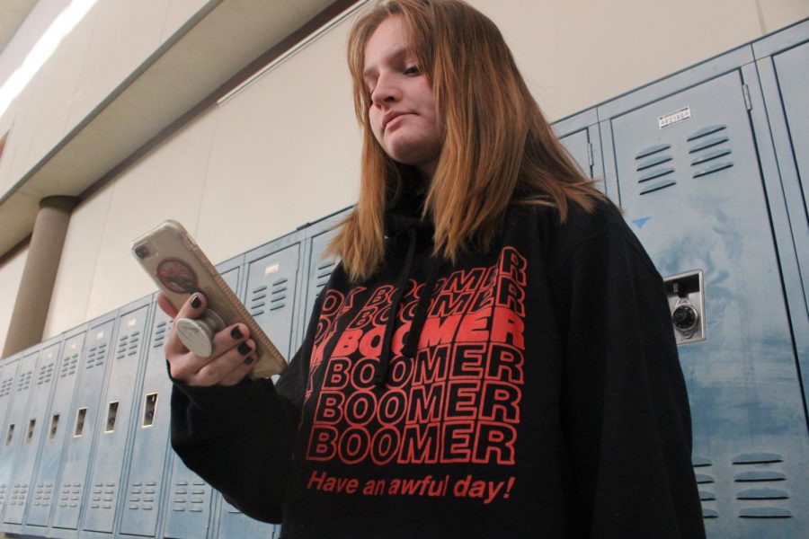 CASUAL SCROLL: Junior, Eleanor Nelson, scrolls through TikTok in her Ok boomer sweatshirt. TikTok is where the meme gained the majority of its popularity.