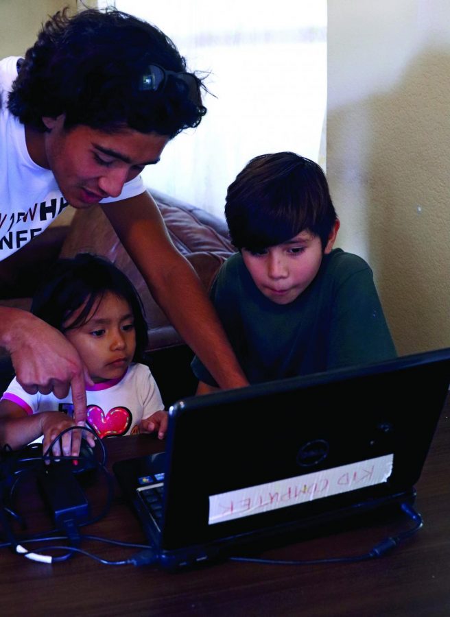 SERVICE WITH A SMILE: Senior Carlos Canepa leads two kids in a computer lesson. The shelter uses volunteers to provide academic tutoring services for their residents. *Identities of the non-high school students have been withheld for privacy reasons.