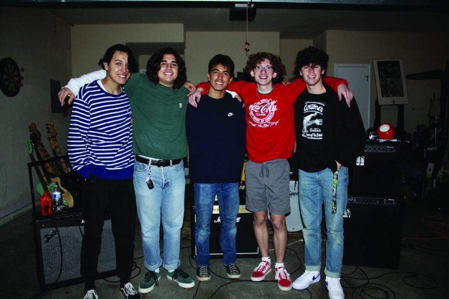 ALL SMILES: The band “Frog Town” poses for a group photo after a garage performance. Frog
Town orginally was a five membered band, but because band member Frankie Caballero left for
college (middle), there are now four musicans in the band.
