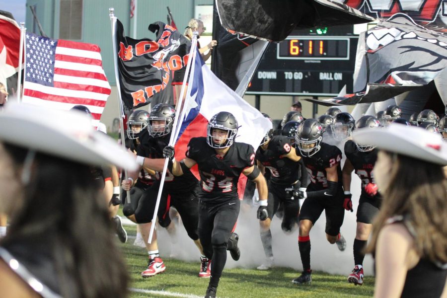 RUNNING DOWN THE FIELD: Senior Noah Camacho carries the Texas flag before the start of the homecoming game.
