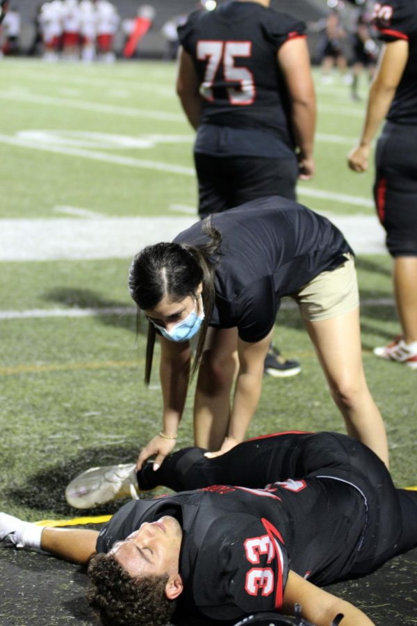 ASSISTING ATHLETES: Senior linebacker John Straw gets help from new trainer Lauren Maldonado. The Bulldogs took home the win over Del Valle with a final score margin of 35-7. 