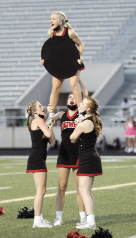 LOUD AND PROUD: Senior Emma Jellison gets lifted into the air at the Del Valle game. Performing difficult stunts and hyping up fans is a large part of cheering at football games.