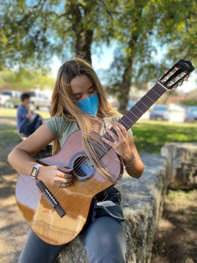 PRACTICING+AT+THE+PARK%3A+freshman+Besa+Carney+plucks+notes+on+her+acoustic+guitar.+Carney+has+been+playing+guitar+for+over+11+years.