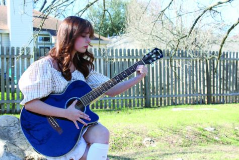 STRUMMING A TUNE: Sophomore Sharon Carson plays music on her guitar outside. Carson decided to pursue her interest in music, and that hobby has developed into a passion.