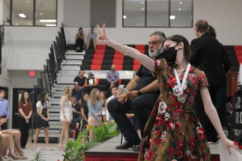 PEACE OUT: Senior Madelyn Lopez Ball expresses her excitement walking off the stage as she gets her certificates and medals. The ceremony was held on Tuesday, May 10 2022 in the new athletic facility. 