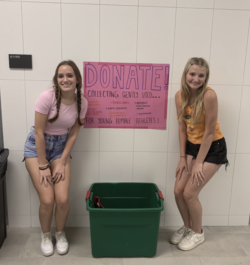 MAKING A CHANGE: Juniors Izzy Detrich and Wes Warmink stand by their donation bin for gently used sports equipment in the girls’ locker room. The pair of athletes distribute the equipment to aspiring female athletes around the city. 