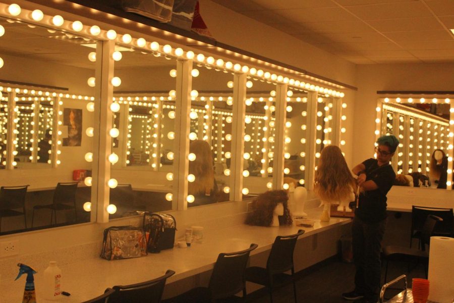 IN THE ZONE: Senior Cailyn Scott brushes a wig in the makeup room. Featured in the new facility, the makeup room is equipped with proper lighting, seating, and mirrors for actors to prepare for performances. 