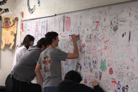 DECORATING THE BOARD: Seniors Rowan Pacconne (left), Ty Jones (second from left), Tyler Haynes (second from right), and Enrique Ramirez (right) continue the tradition of decorating their classroom’s whiteboard for the upcoming year. All four students are members of the Bowie Toons Animation club sponsored by CTE teacher Andrew Nourse.