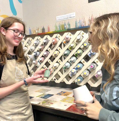 IMPECCABLE CUSTOMER SERVICE: Junior Iris Carpenter explains how to use a painting pen to a customer at Cafe Monet: Art & Clay Studio. Carpenter started working at Cafe Monet this summer and it is her first job.