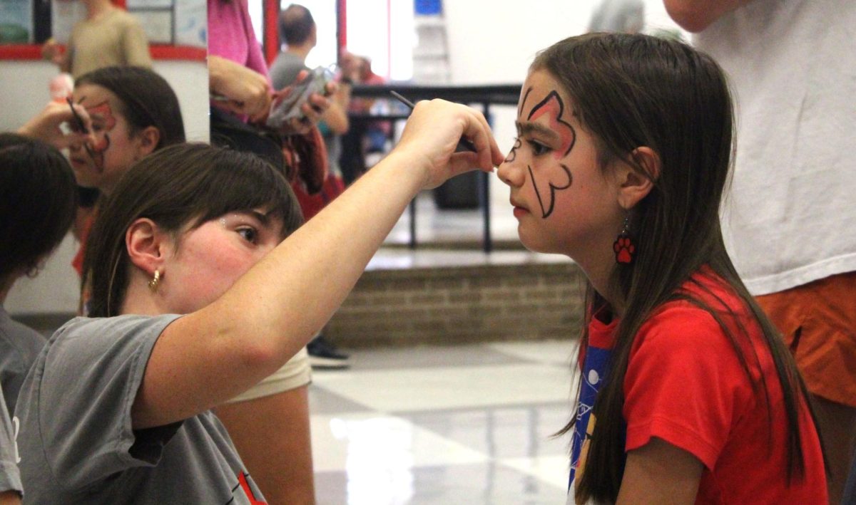 FACE PAINTING: Senior Brighton Toland painted faces for kids at Bulldogs and Hotdogs. Toland and others were a part of the Starlight Theater Company’s booth. “If I could, I would volunteer again next year. It’s so much fun,” Toland said.