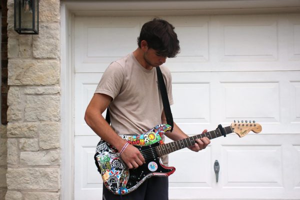 Belkin plays one of his guitars outside of his house.