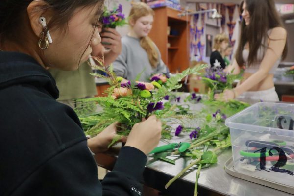 DESIGNING A DISPLAY: Sophomore Mya Mendoza gracefully arranges flowers and leaves into a bouquet. The personalized bouquet will be sold to a Bulldawg Blooms customer.