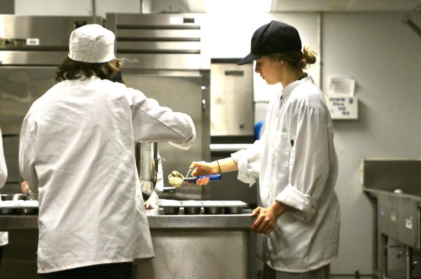 FILLING THE MUFFIN TRAY: In the loud, bustling culinary classroom, seniors Erin Cain and Bodhi Rosen collaborate in perfect harmony, working together to focus on creating fresh banana bread muffins for the hungry student body. Cain carefully scoops the banana muffin batter into a muffin tray, while Rosen holds the edges of the batter bowl, keeping it steady for the next scoop. “There was a lot of thought and care that went into the baking process,” Rosen said.