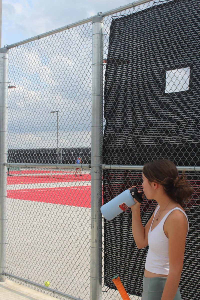 STAYING HYDRATED: Sophomore Abby Laine hydrates in the shade. New AISD rules require more water breaks for student athletes. 