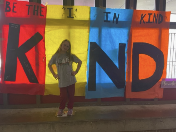 Freshman Abby Ray poses in front of the Be the I in Kind poster.