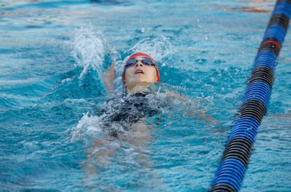 KICKING HARD: Freshman Kate Alexander swims the backstroke race. Alexander holds a personal best time of one minute and 46 seconds in the 100 meter backstroke.