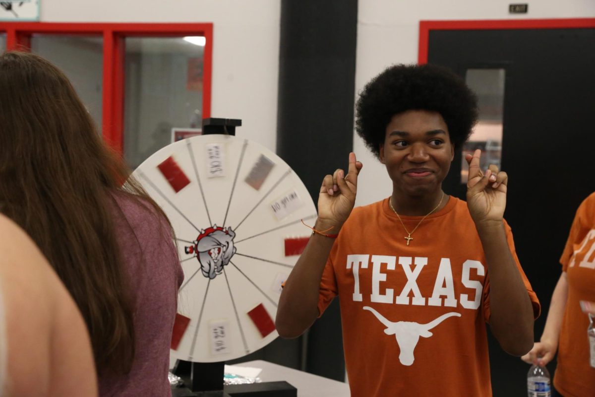 FINGERS CROSSED: Senior John Walton crosses his fingers in hopes to win a gift card worth up to 25 dollars. Walton wears his Texas shirt in honor of his plan to attend UT of Austin. “I liked the karaoke at senior day,” Walton said “It was really funny seeing everybody sing in front of a crowd.”