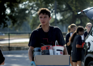 REMOVING RECYCLEABLES: Senior Aiden Wettengel carries paint products from a drop-off car to be placed in a color guard parent driver truck which then will be taken to the recycling center. BOPA, a recycling event sponsored by Bowie color guard ran from 9 a.m. to 12 p.m. on Saturday Sept.14. 