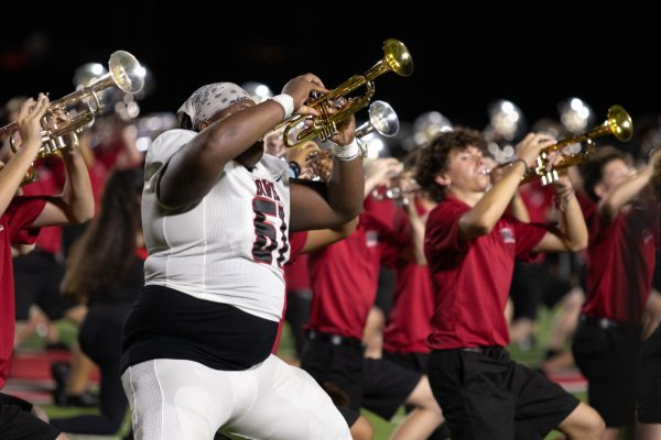 BALANCING BAND: Senior football player Cedric Walls quickly hurries onto the field after the 2nd quarter to perform alongside the band. Walls has been in band and football since his freshman year. “After school on game days, I get dressed in my gear and go straight to football,” Walls said. “After that I come down to band to get my instrument and vipers and then I head to the game. I usually get home at around midnight.”