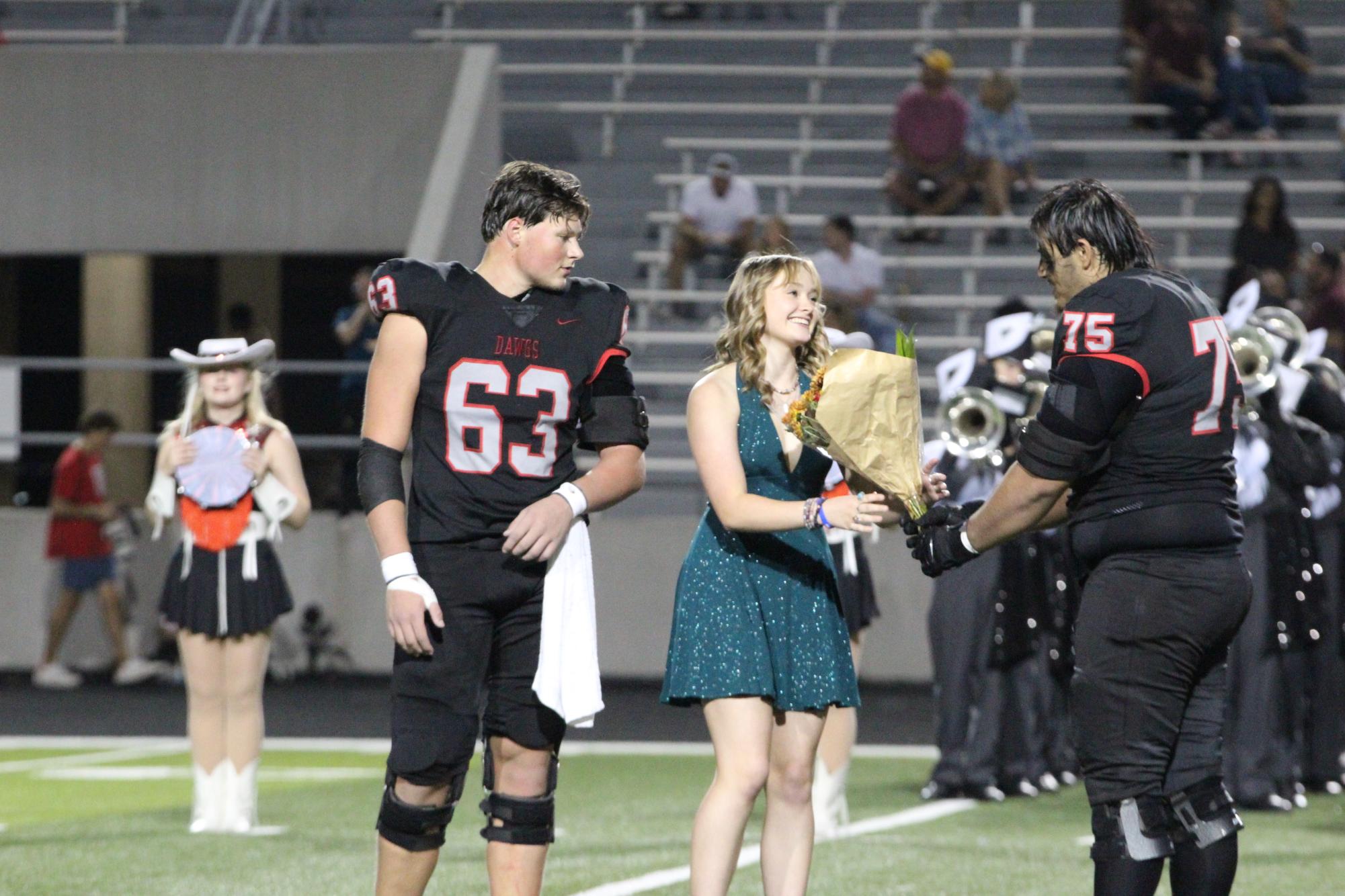 SENIOR SWEETHEART: Senior varsity football trainer Manning Adkins accepts flowers from senior Carlos Ortiz in honor of being named Senior Sweetheart. The varsity football team chooses a Senior Sweetheart every year. “Walking onto the field felt magical and made me really appreciate the friendships I have made,” Adkins said. “I also felt really proud of myself and all the hard work I put in to get to that moment.”