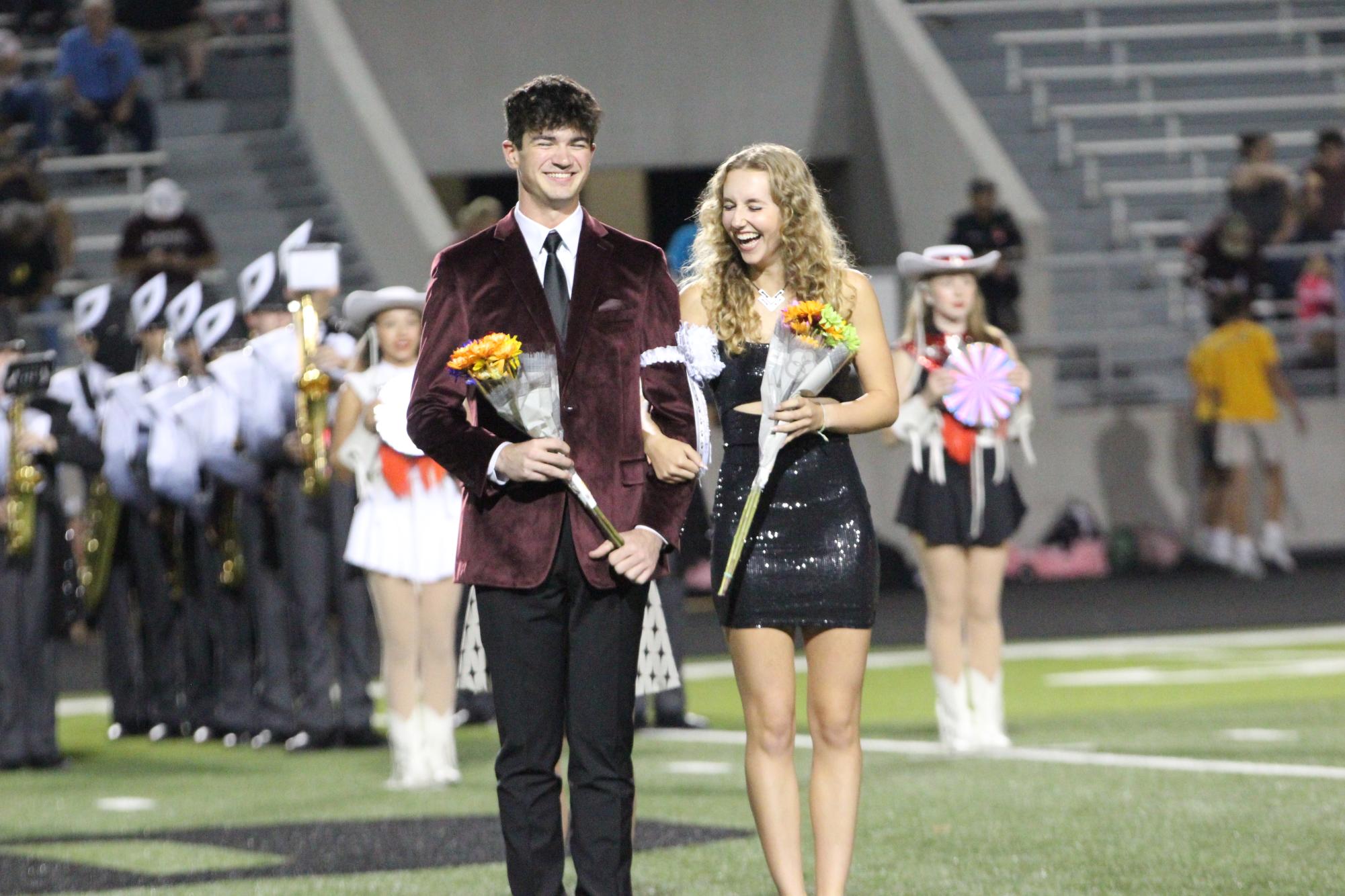 BAND SWEETHEART: Senior drum major Sophia Thollander stands on the field with her escort while being named Band Sweetheart. Thollander ran for homecoming court alongside Bubba Infante. “It made me happy that I was given the opportunity to walk out and represent the band,” Thollander said. “It was super cool to dress up and walk out on the field with everyone.”