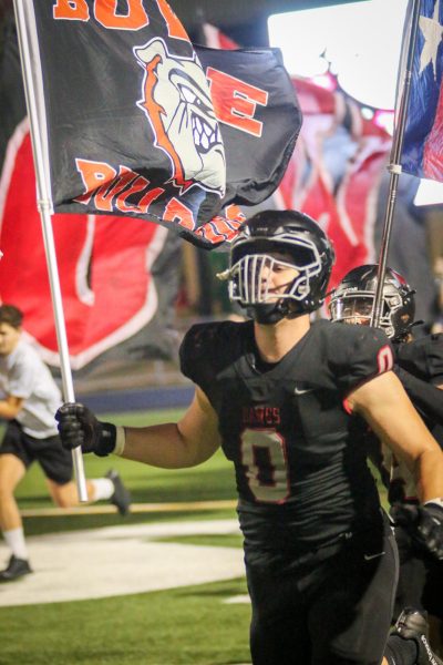 LEADING OUT THE PACK: Junior captain Jackson Lang carries out the flag as the ‘Dawgs take the field vs Dripping Springs. The ‘Dawgs narrowly lost the homecoming game 38-35.