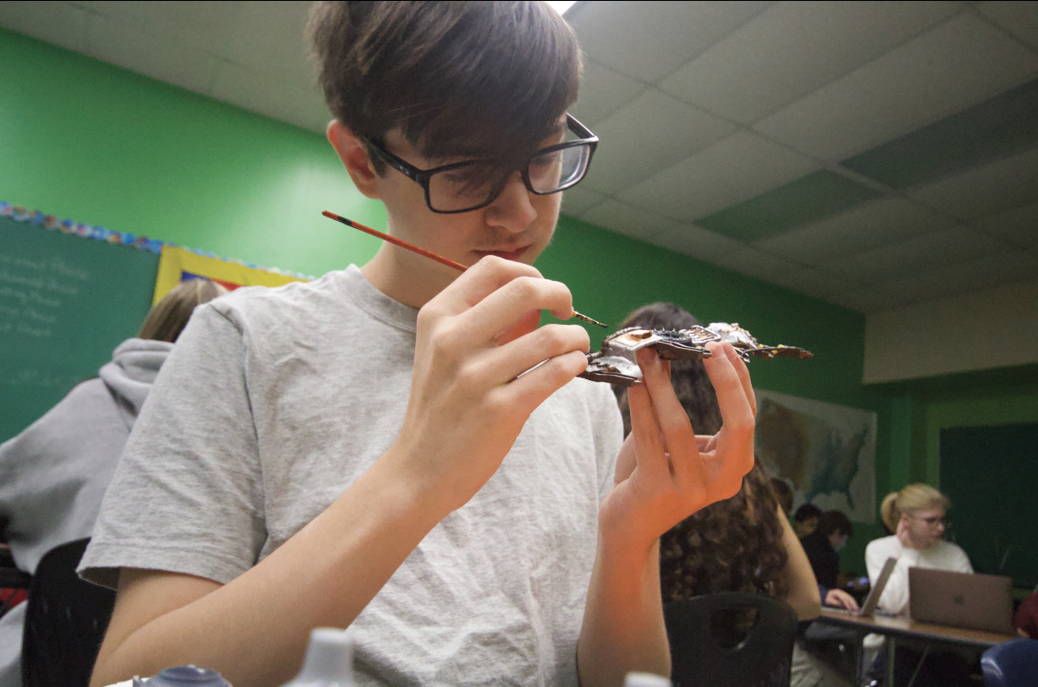 SENIOR STUDIES HIS MASTERPIECE: Bristle by bristle Quinn Wilkinson puts the finishing touches on his scrap yard piece for figures to have cover in battle. Club members will often design tiny pieces to fill up the table. 