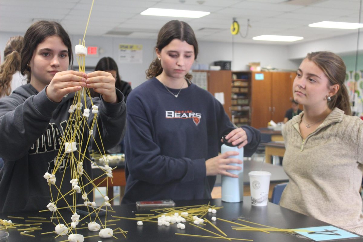 BUILD, TAKE A BREAK AND OBSERVE: Seniors Clarie Tucker, Caroline Cullen and Maya Dudek, build a spaghetti and marshmallow structure during a club meeting for the Society of Women Engineers. Dudek is one of the presidents of the club and took on an observing role.