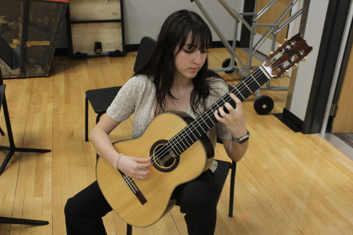 STRUMMING ALONG: Senior Jianna Zamora strums along in Guitar class. Zamora is the teachers assistant for the guitar classes. 